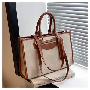Detail of canvas contrast tote bag with leather trim on a book by window shutters