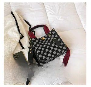 Detail of checkered tote bag with woven texture, golden twist lock and wide fabric strap