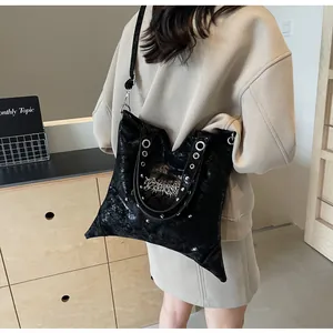 Dettaglio di una grande borsa tote nera lucida con occhielli metallici e ricami