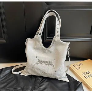 Dettaglio borsa argento metallizzato con borchie punk e accenti di occhielli sulla tracolla
