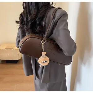 Brown vintage baguette bag with plush keychain shown on a grey blazer shoulder style