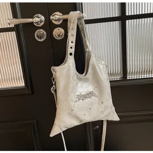 Dettaglio della borsa a tracolla argento stile industriale con rivetti e logo gotico