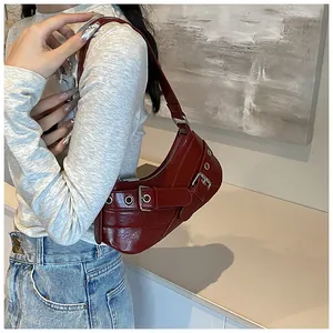 Detail of burgundy crescent shoulder bag with metallic eyelets and shiny leather finish