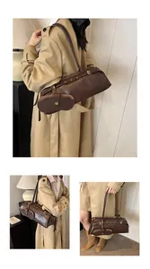 Detailed view of deep brown glossy leather cylindrical bag with metal buckle straps