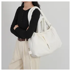 Detail view of large white quilted puffer tote bag shown on model with plush shoulder strap