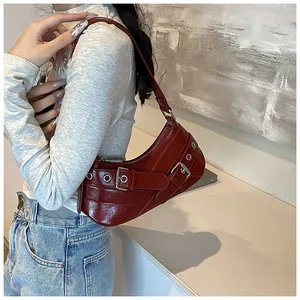 Detail of dark red hobo bag with metallic eyelets and punk style buckles on leather