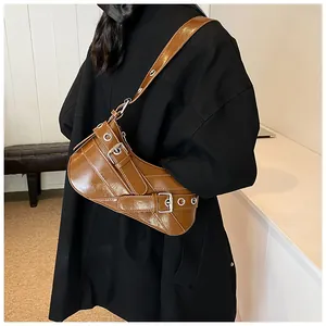 Detailed view of caramel PU leather bag with punk metal buckles and eyelets detail