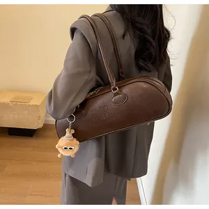Detail of vintage dark brown leather boston bag with embossed brand logo and furry charm