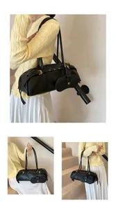 Detail of black leather shoulder bag with gold buckle straps and round charm pouch