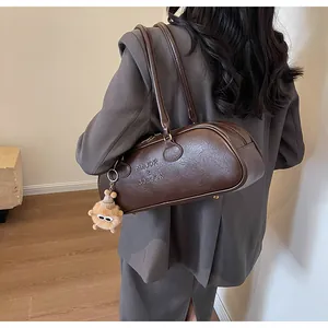 Detail of dark brown baguette bag with pleated leather texture and plush monster charm