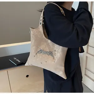 Dettaglio della borsa a tracolla a stella con finitura metallica e logo a spina su abito nero