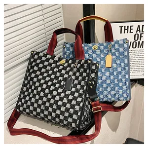 Detailed macro view of woven checkerboard denim tote bag with gold metal twist lock