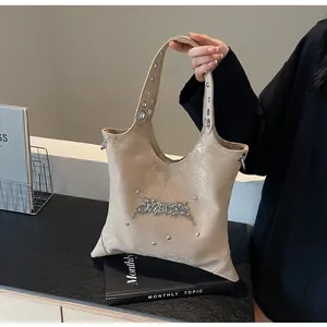 Dettaglio borsa hobo beige metallizzata con logo gotico argento e tracolla con occhielli