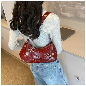 Detail of burgundy glossy leather underarm bag with decorative silver eyelets and buckle