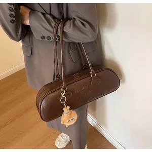 Detail of vintage dark brown baguette bag with embossed logo and plush charm