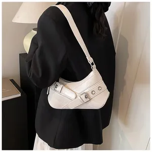 Detail view of cream white baguette bag with decorative metallic eyelet belts and hardware