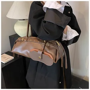 Detail of dark brown leather shoulder bag featuring metal eyelets and belt buckle accents