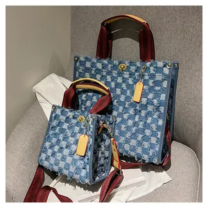 Detail of blue checkered denim tote bags with frayed edges and red woven straps