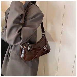 Detail of dark brown glossy patent leather underarm bag with silver buckle straps