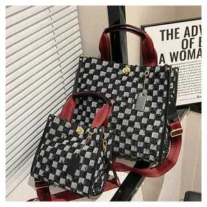 Detail of checkered denim tote bag featuring dual sizes and stylish red fabric straps
