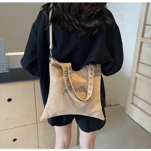 Dettaglio della borsa tote color albicocca con borchie punk e logo metallico argento