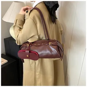 Detail view of burgundy leather shoulder bag with belt buckles and mini pouch attachment