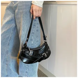Close-up of black glossy Y2K shoulder bag with silver eyelets and buckle details