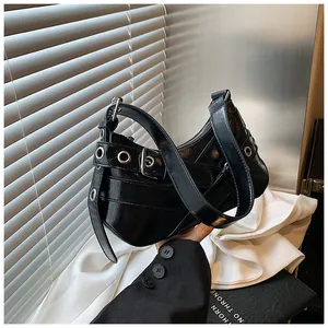 Detail of black glossy underarm bag with silver metal eyelets and punk style buckle