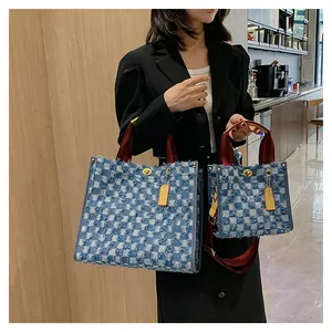 Detail view of denim checkered tote bags in two sizes with red striped handles and metal locks