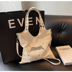 Dettaglio borsa hobo beige con occhielli in metallo sulla tracolla e decori in argento