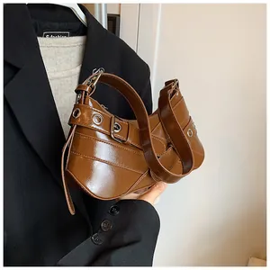 Close-up of brown glossy leather bag with decorative buckle and metal eyelet details
