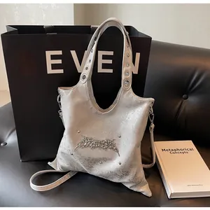 Dettaglio borsa tote argento metallizzato con texture increspata e borchie su pelle nera