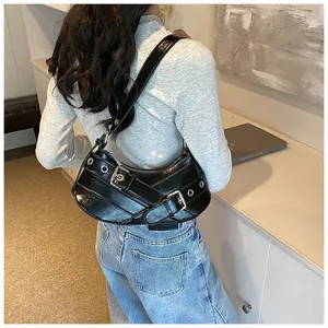 Detail of black glossy crescent bag featuring silver buckles and eyelets on shoulder strap