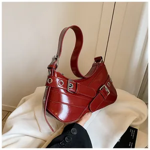 Detailed macro view of dark red patent leather bag with silver eyelets and metal buckles