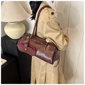 Chic burgundy leather baguette bag with metal buckle detail worn over the shoulder
