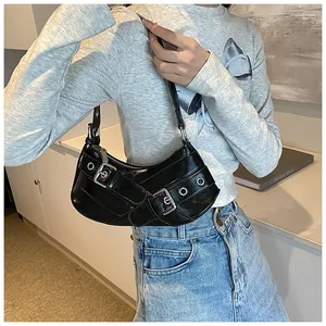 Detail of black patent leather underarm bag with silver buckles and punk eyelet straps