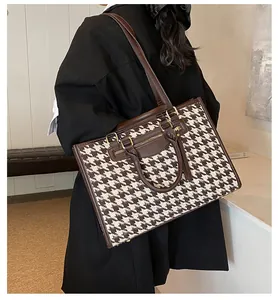 Detailed view of houndstooth tote bag featuring premium leather trim and metal buckle