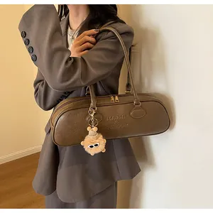 Brown faux leather bowling bag with logo detail and a cute plush monster charm