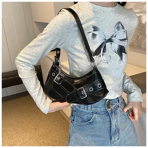 Detail of black faux leather underarm bag with silver buckles and Y2K aesthetic metal holes