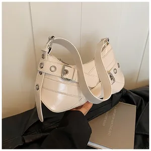 Detailed close-up of cream faux leather shoulder bag with silver eyelets and buckles