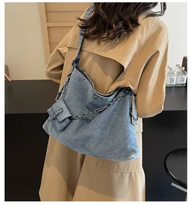 Detail of light blue denim tote with silver chain and detachable pouch on a model