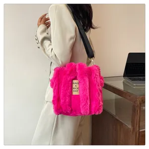 Detail of rose pink plush tote bag with black canvas strap and yellow slogan patch