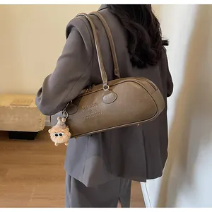 Detail showing retro brown cylinder bag with branding and fuzzy charm on grey blazer