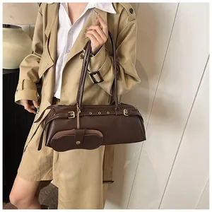 Detail view of deep brown leather baguette bag with gold metal buckle and mini pouch charm