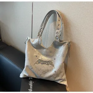 Dettaglio borsa tote argento con decorazioni a spina e tracolla con occhielli