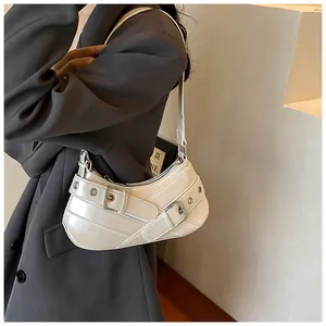 Detail of white patent leather hobo bag with metal eyelets and decorative buckles