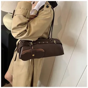 Detailed close-up of dark brown leather shoulder bag with vintage gold metal buckles