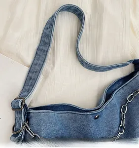 Detailed close-up of blue denim tote bag featuring wide shoulder strap and metallic chain