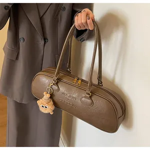Close-up of brown textured leather bowling bag with logo detail and plush charm