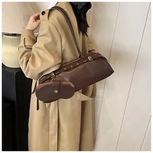 Detail view of deep brown baguette bag with belt buckle and metallic eyelets design